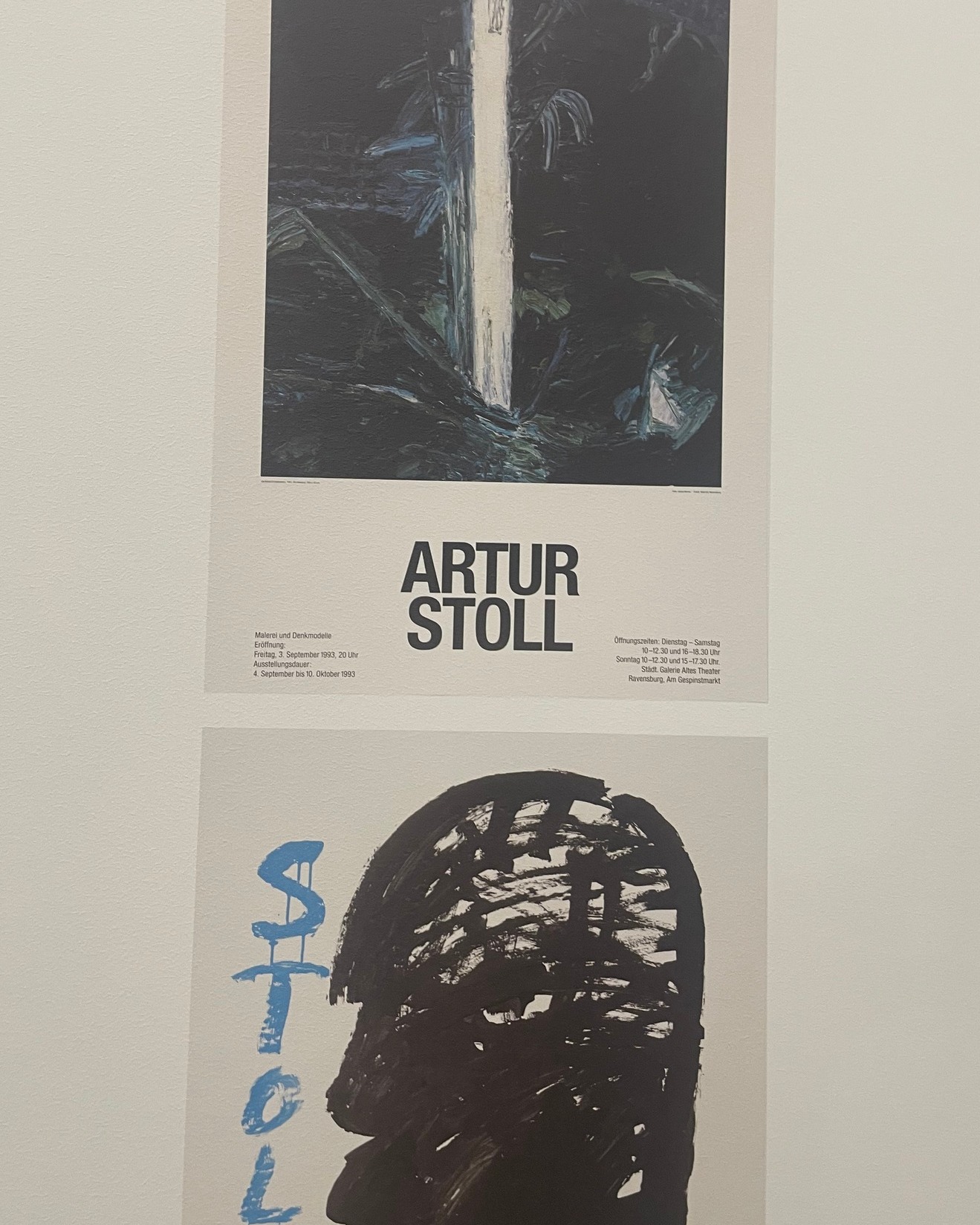 Dieser Alternativtext wurde KI-generiert: Schwarz-weißes Foto einer Ausstellungstafel mit Informationstext und darunter ein Kunstwerk mit einem Porträt. Die Tafel enthält Öffnungszeiten und Ausstellungsdetails.