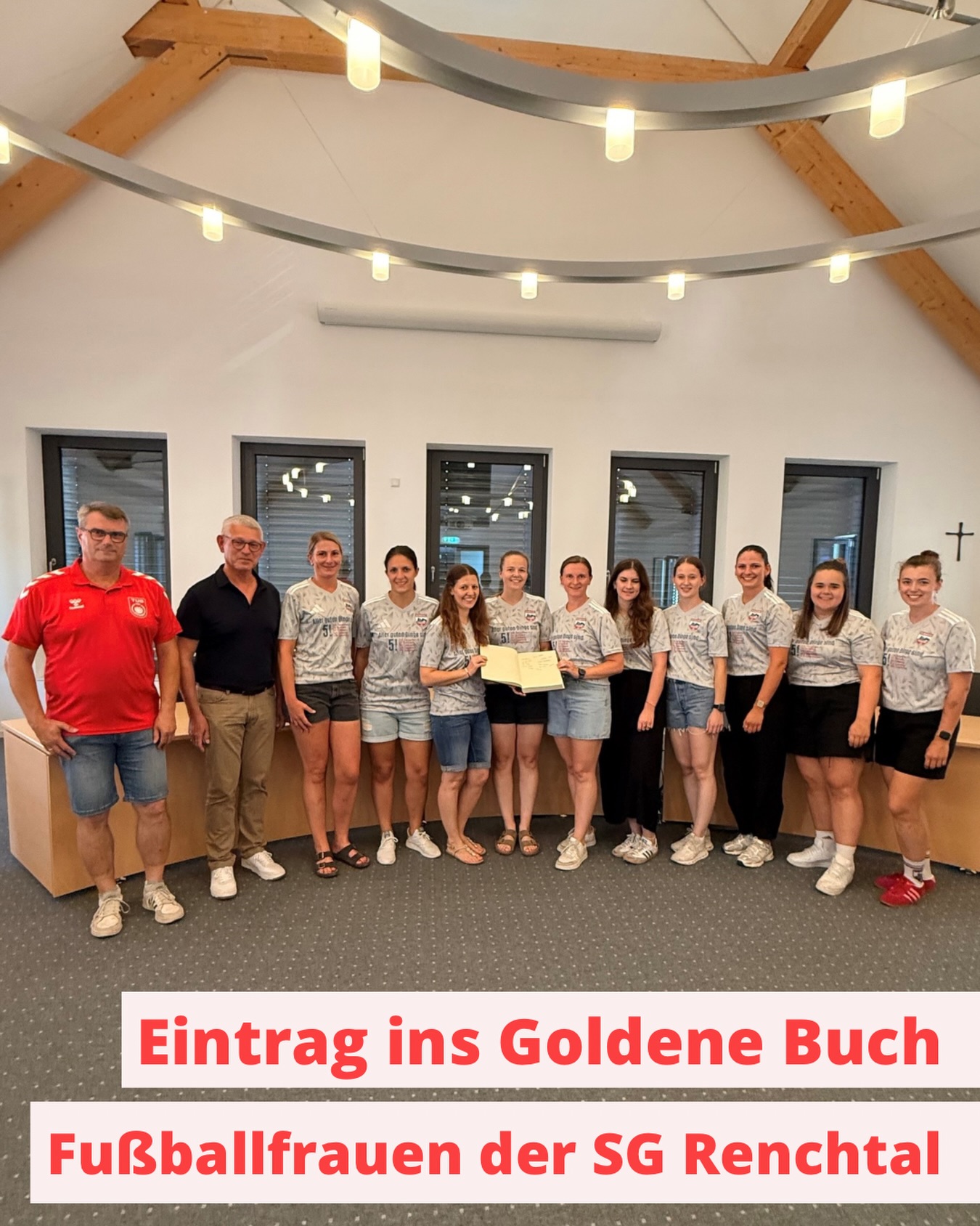 Eine Gruppe von Personen in grauen Trikots und zwei weitere Personen stehen nebeneinander in einem hellen Raum. Zwei der Personen in Trikots halten ein offenes Buch. Ein Textfeld unten lautet: "Eintrag ins Goldene Buch Fußballfrauen der SG Renchtal". (KI-Alternativtext)