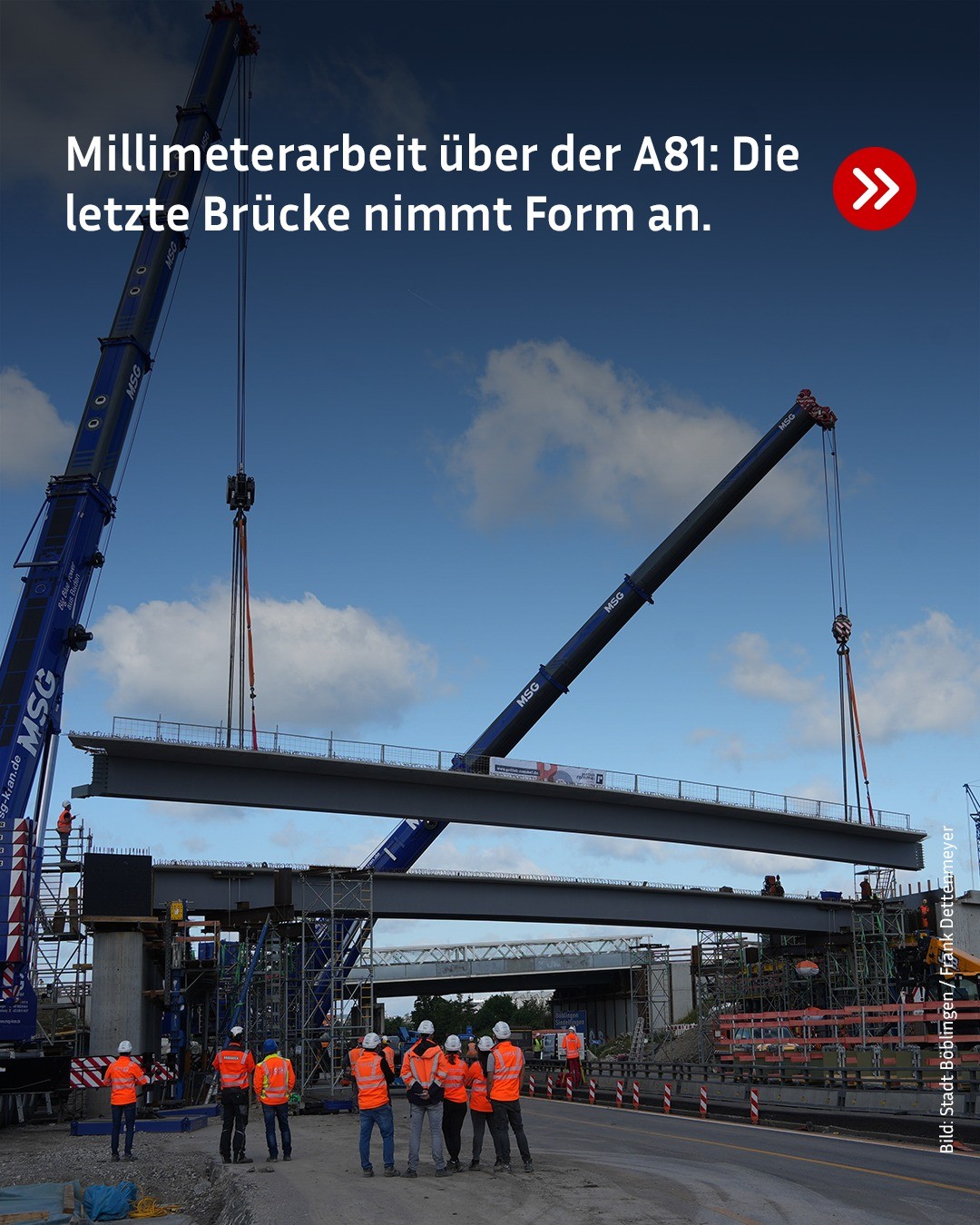 Zwei große Kräne heben ein Brückensegment über einer Autobahn, während mehrere Personen in Warnwesten und Helmen am Boden beobachten. Der Himmel ist blau mit weißen Wolken. Über dem Bild steht: „Millimeterarbeit über der A81: Die letzte Brücke nimmt Form an.“ (KI-Alternativtext)