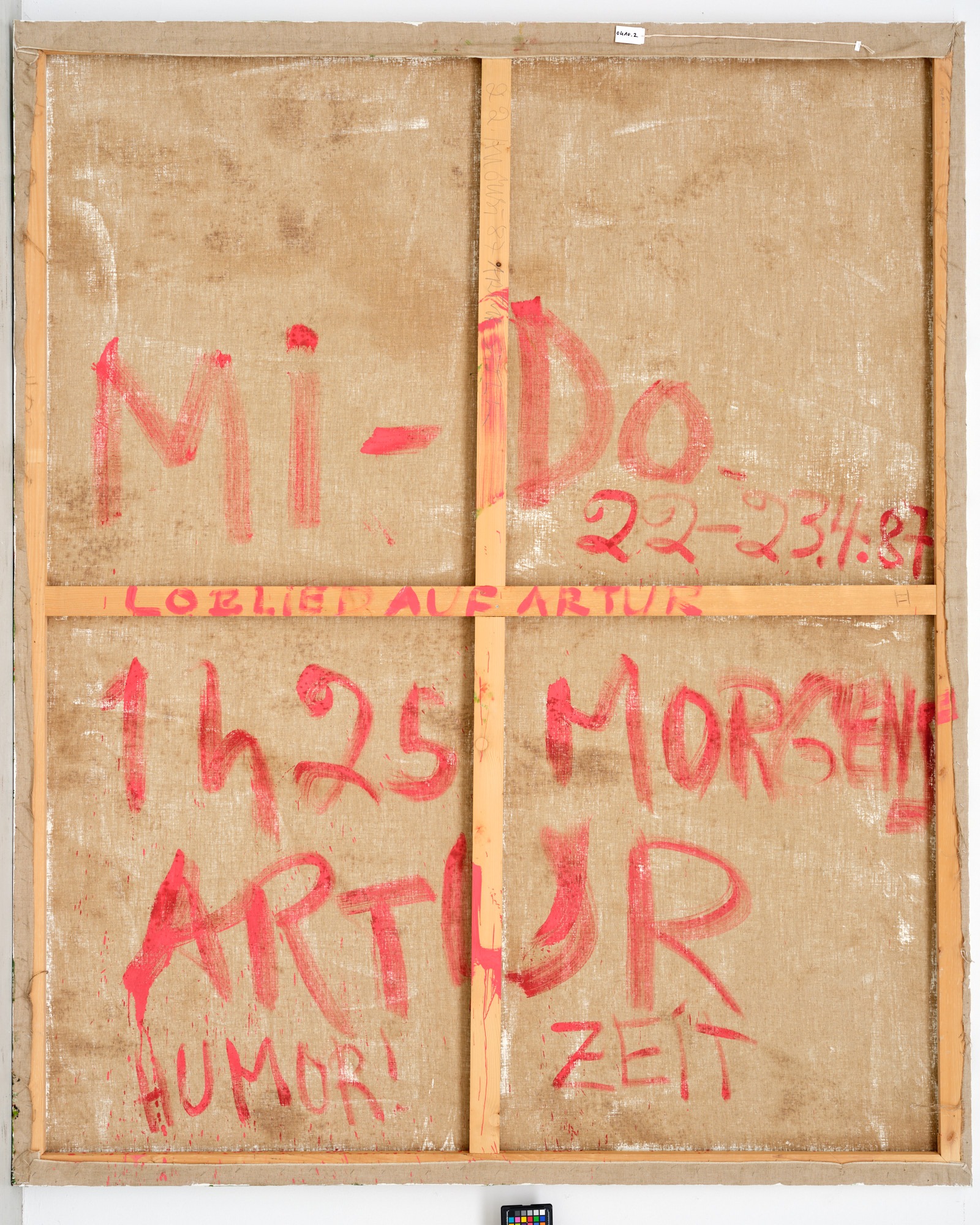 Dieser Alternativtext wurde KI-generiert: Es ist die Rückseite eines bemalten Objekts. Auf dem beigen Untergrund sind rote Buchstaben und Zahlen zu sehen.