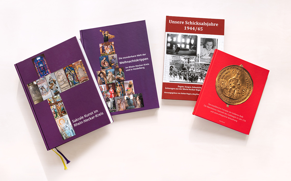 Dieser Alternativtext wurde KI-generiert: Mehrere Bücher unterschiedlicher Farbe liegen auf einer weißen Oberfläche. Die Buchcover zeigen historische Fotografien und Illustrationen.