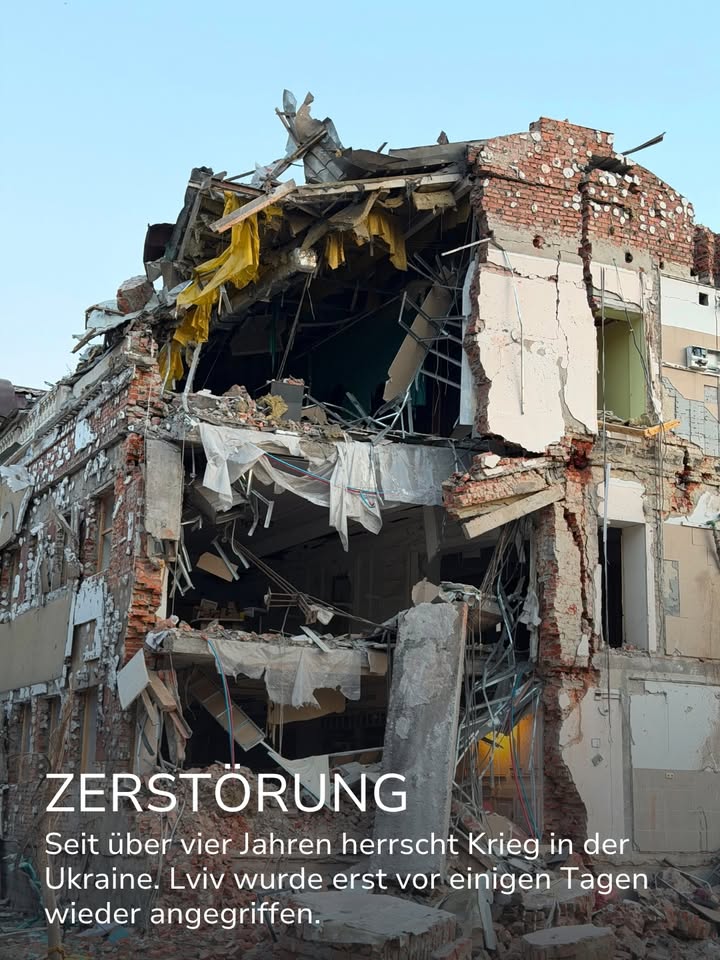 Stark beschädigtes Gebäude mit eingestürztem Dach, freiliegenden Ziegelsteinen und hängenden Trümmern. Der weiße Text im Vordergrund lautet „ZERSTÖRUNG“ gefolgt von: „Seit über vier Jahren herrscht Krieg in der Ukraine. Lviv wurde erst vor einigen Tagen wieder angegriffen.“ (KI-Alternativtext)