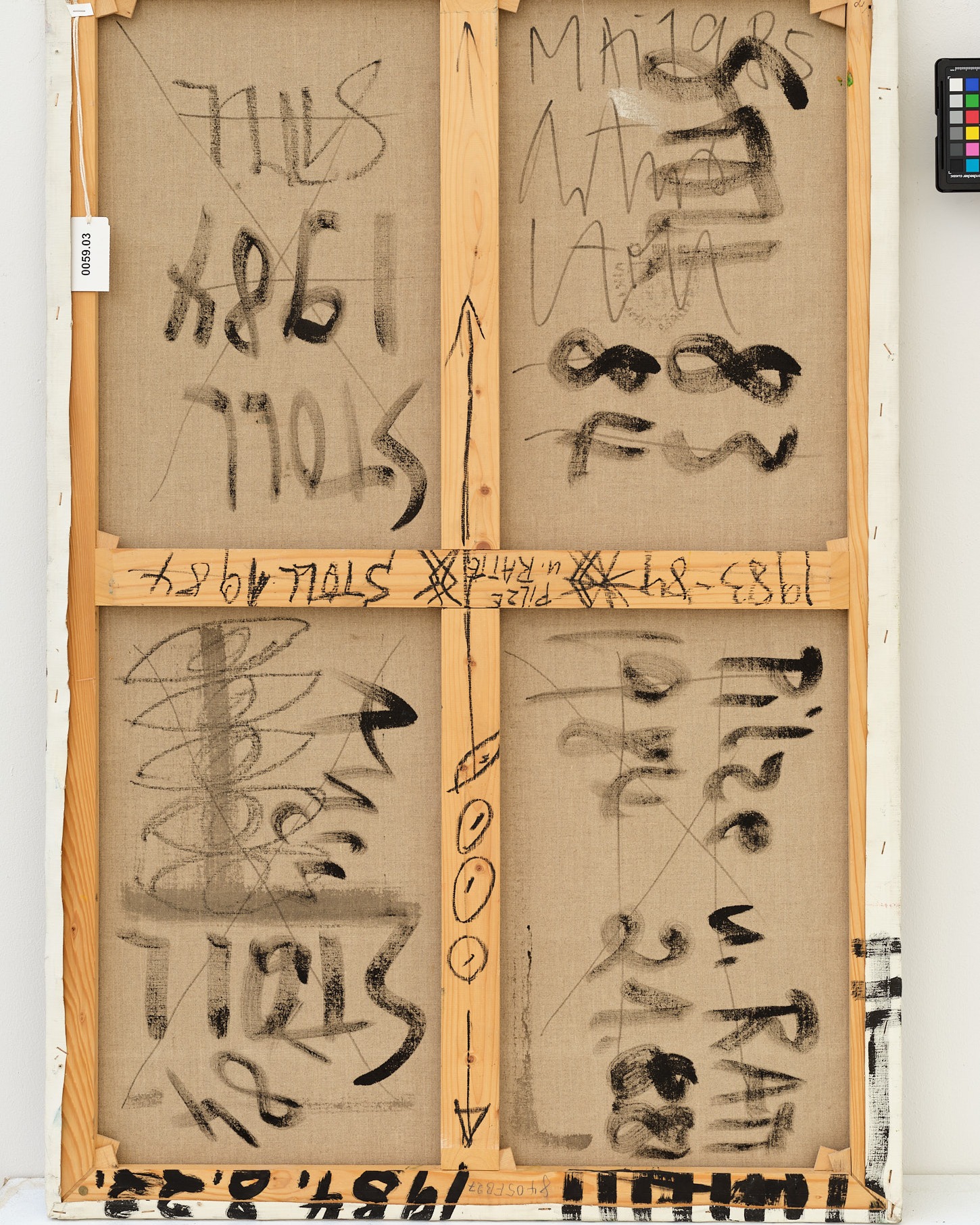 Dieser Alternativtext wurde KI-generiert: Schwarz-weißes Foto einer Holzrückseite, die mit zahlreichen Kritzeleien, Zahlen und Schriftzügen bedeckt ist. Die Beschriftungen sind in dunkler Farbe aufgetragen und wirken chaotisch.