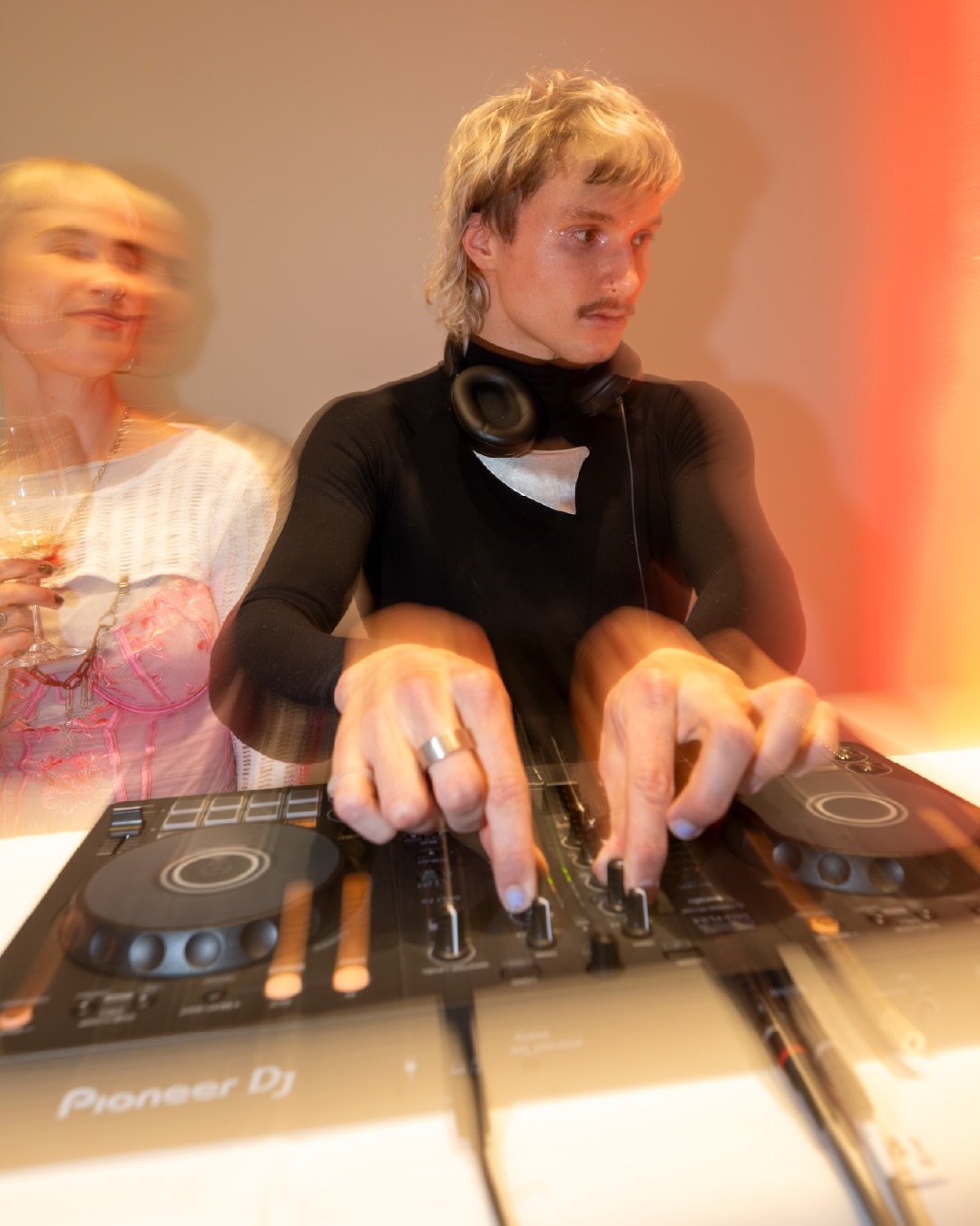 Dieser Alternativtext wurde KI-generiert: Eine Person steht an einem Mischpult und bedient es. Im Hintergrund ist eine weitere Person zu erkennen, die etwas hält.