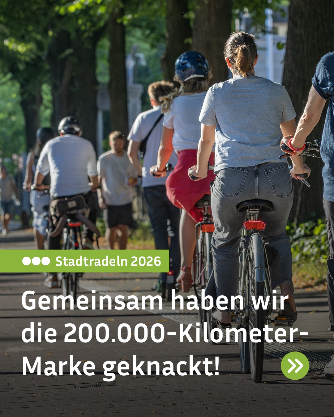 Menschen fahren auf Fahrrädern auf einem Weg durch eine Baumallee. Ein grüner Balken zeigt den Text „Stadttradeln 2026“. Darunter steht groß: „Gemeinsam haben wir die 200.000-Kilometer-Marke geknackt!“. Unten rechts ist ein grünes Symbol mit zwei Pfeilen zu sehen. (KI-Alternativtext)