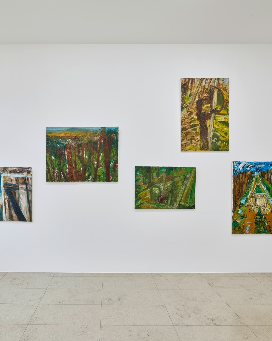 Dieser Alternativtext wurde KI-generiert: An einer hellen Wand hängen mehrere farbenfrohe Gemälde mit Waldmotiven. Der Raum verfügt über einen hellen Fliesenboden.